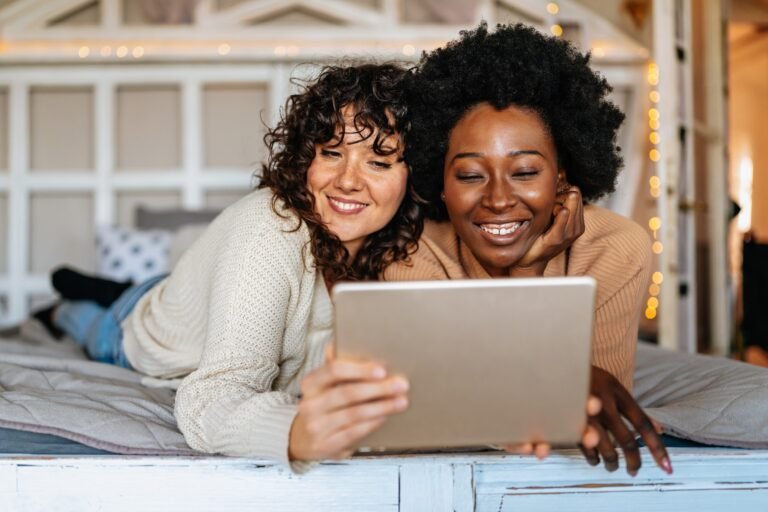Beautiful happy gay couple having fun and good time together with tablet at home