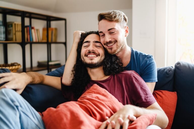 Romantic gay couple tender cuddling in the living room sofa