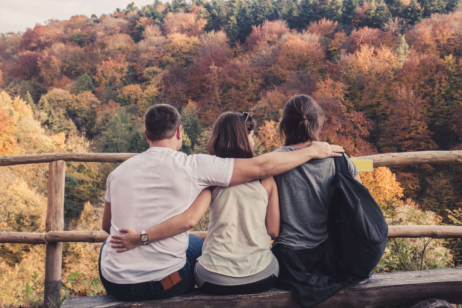 Three,People,Hugged,Each,Other,Sitting,On,Wooden,Benches,And